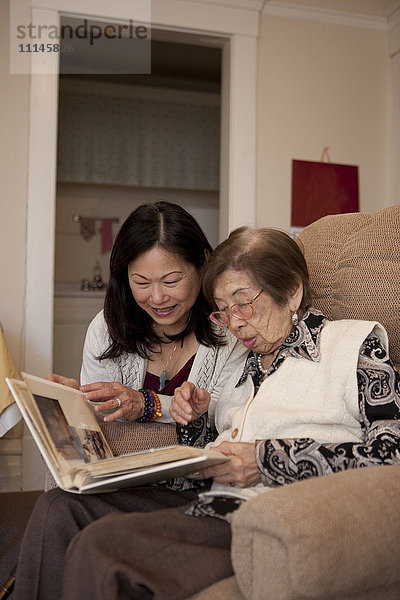 Asiatische Mutter und Tochter betrachten ein Fotoalbum