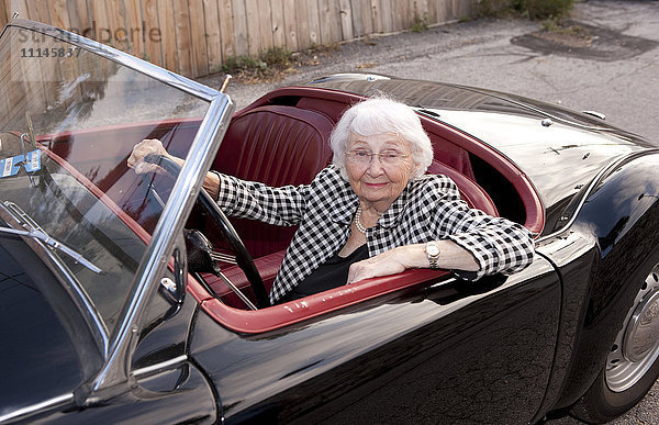 Lächelnde ältere Frau fährt Cabrio