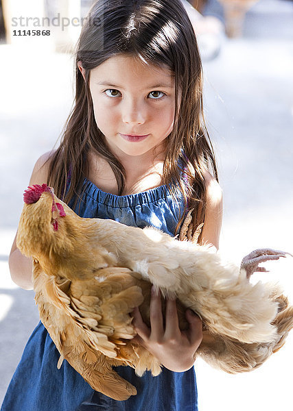 Gemischtrassiges Mädchen hält Huhn