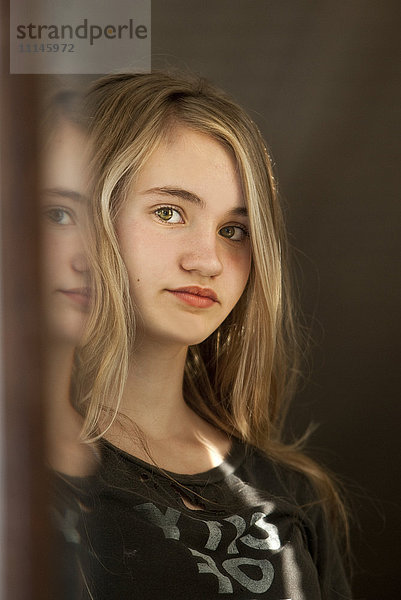 Ernstes Teenager-Mädchen  das sich im Spiegel betrachtet