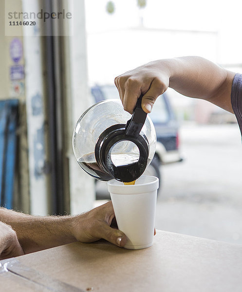 Arbeiter schenken eine Tasse Kaffee im Lagerhaus ein