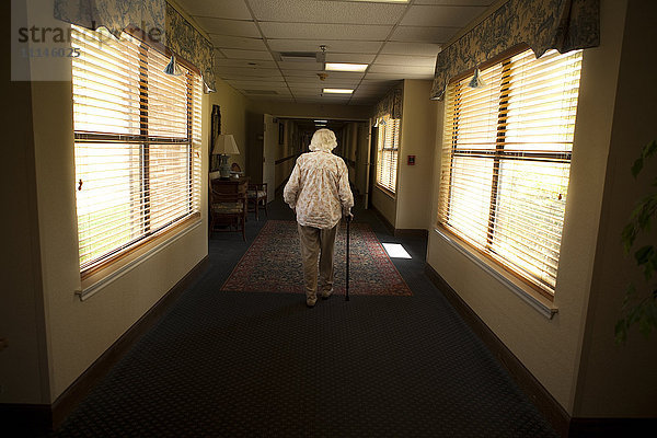 Ältere kaukasische Frau geht mit Stock im Altersheim