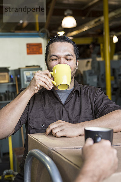 Arbeiter trinkt Kaffee im Lagerhaus