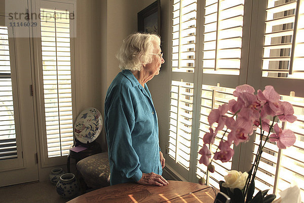 Ältere kaukasische Frau schaut aus dem Fenster