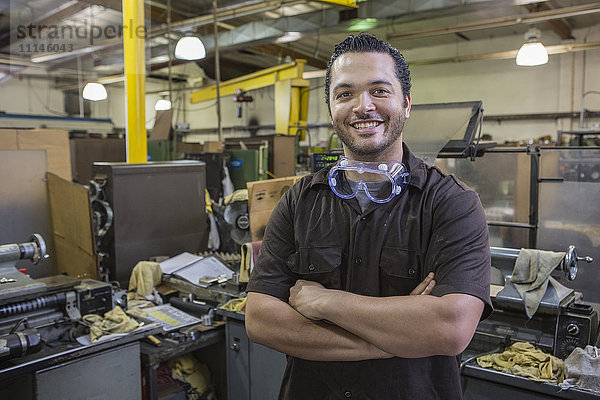 Hispanischer Arbeiter lächelt in der Werkstatt