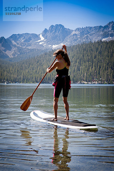 Gemischtrassige Frau auf Paddelbrett in Lake Tahoe  Kalifornien  Vereinigte Staaten