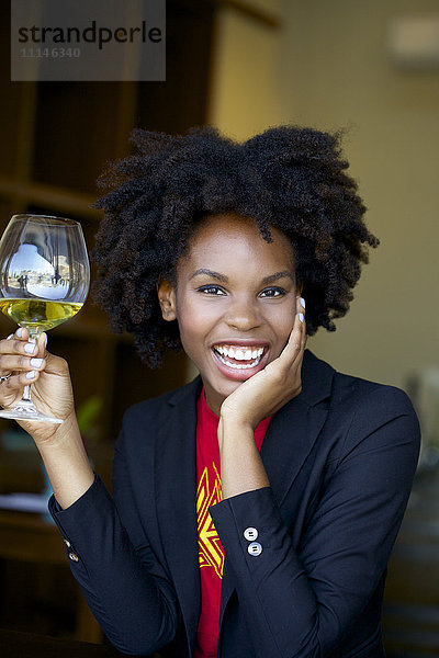 Lächelnde Frau trinkt ein Glas Weißwein