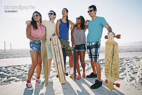 Freunde halten Longboards am Strand