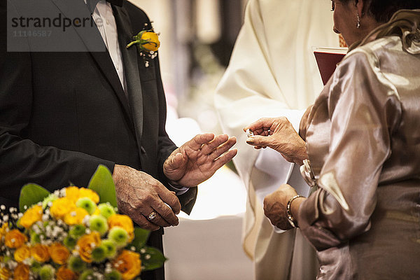 Älteres Paar tauscht bei der Hochzeit Ringe aus