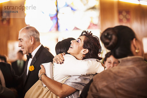 Hispanische Familie umarmt sich bei der Hochzeitsfeier