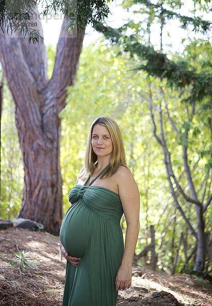 Lächelnde schwangere Frau hält Bauch