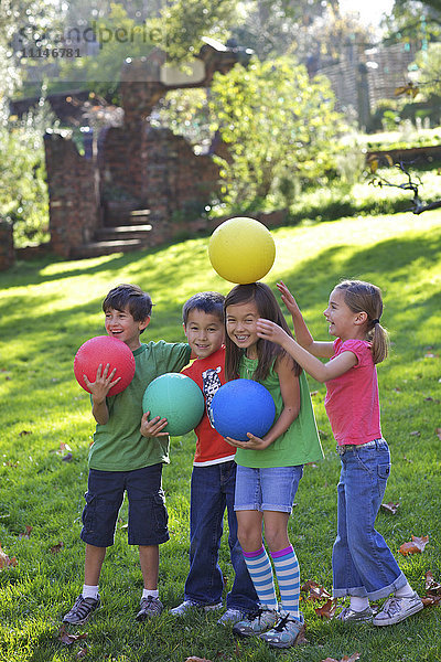 Kinder spielen mit Bällen im Gras