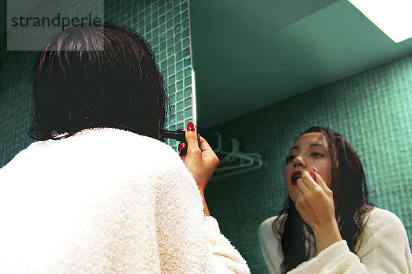 Gemischtrassige Frau  die sich im Spiegel schminkt