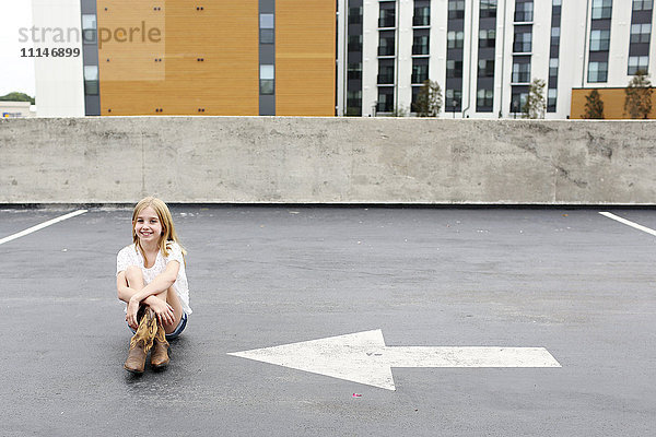 Teenager-Mädchen sitzt auf einem städtischen Dachparkplatz