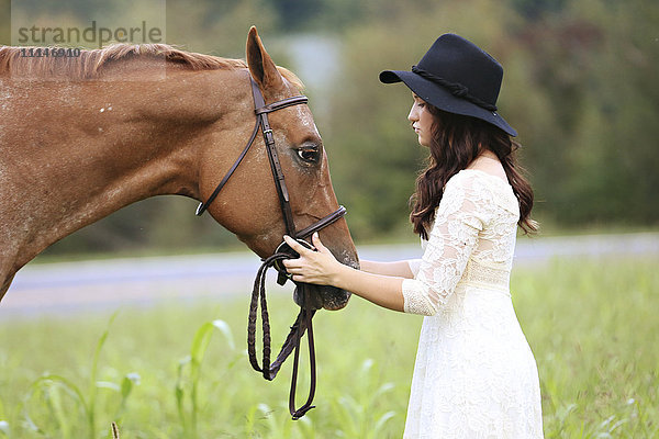 Frau streichelt Pferd in ländlichem Feld