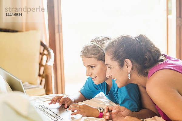 Mutter und Tochter benutzen Laptop am Schreibtisch