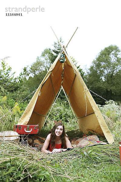 Frau liegt im Campingzelt auf einem Feld