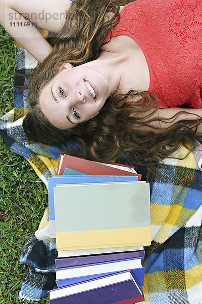 Frau liegt mit Büchern auf einer Decke