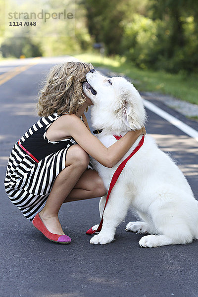 Nahaufnahme eines Mädchens  das einen Hund auf der Straße umarmt