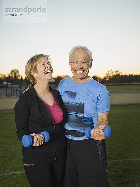 Älteres Paar hebt gemeinsam Gewichte im Stadtpark
