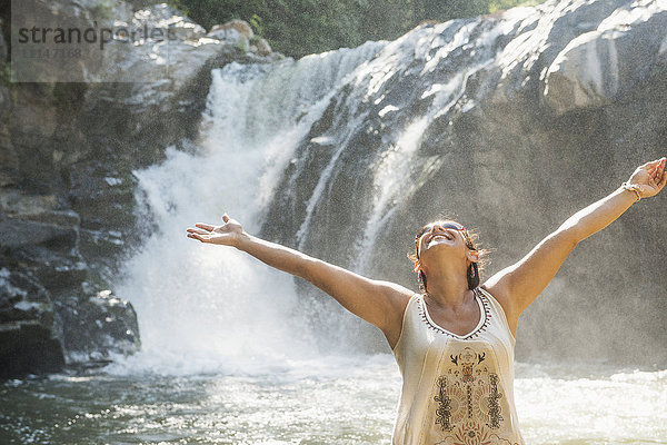 Hispanische Frau steht am Wasserfall