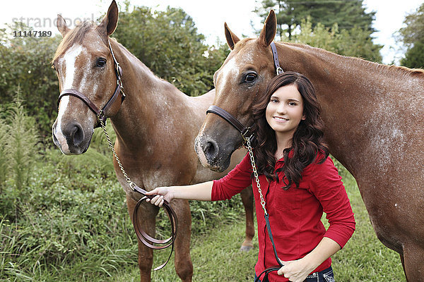 Teenager-Mädchen geht mit Pferden in einem ländlichen Feld spazieren