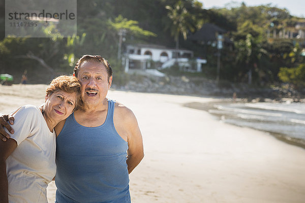 Hispanisches Paar umarmt sich am Strand