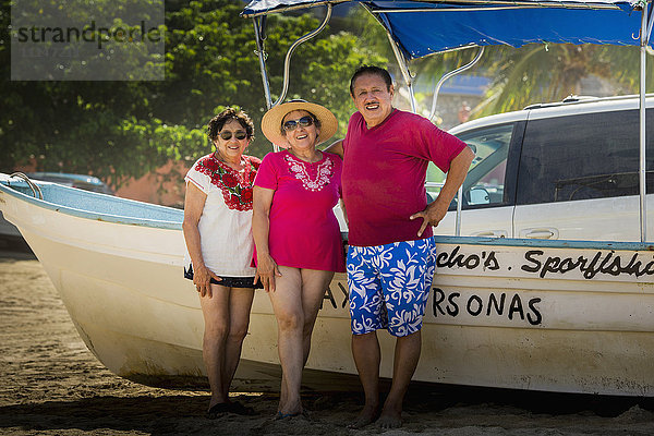 Hispanische Freunde lächelnd mit Boot am Strand