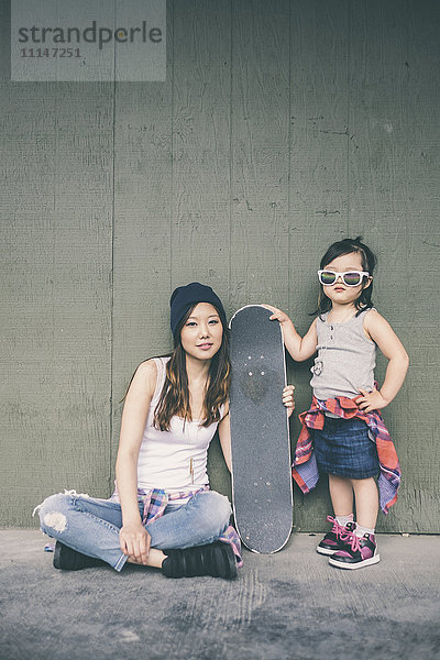 Koreanische Mutter und Tochter posieren mit Skateboard
