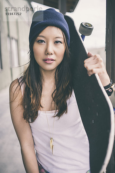 Koreanische Frau mit Skateboard auf der Straße