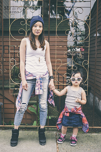 Koreanische Mutter und Tochter halten sich auf der Straße in der Stadt an den Händen