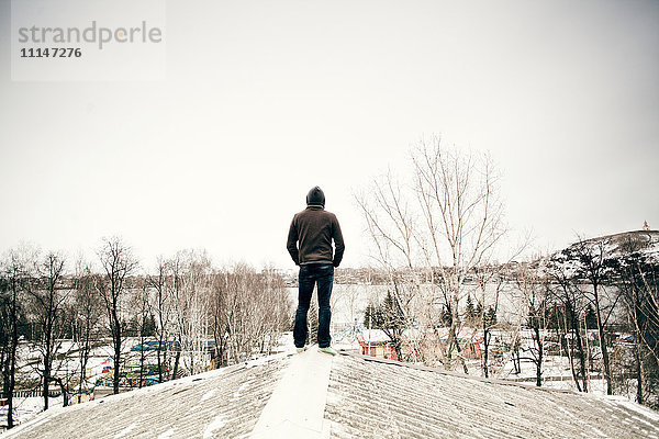 Kaukasischer Mann steht auf einem verschneiten Dach