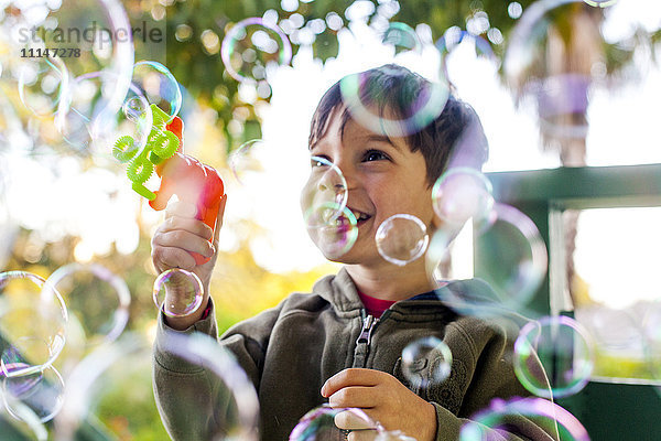 Gemischtrassiger Junge spielt mit Seifenblasen im Freien