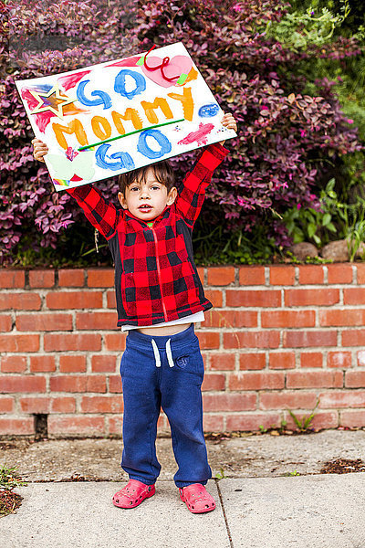 Gemischtrassiger Junge hält Go mommy go -Schild