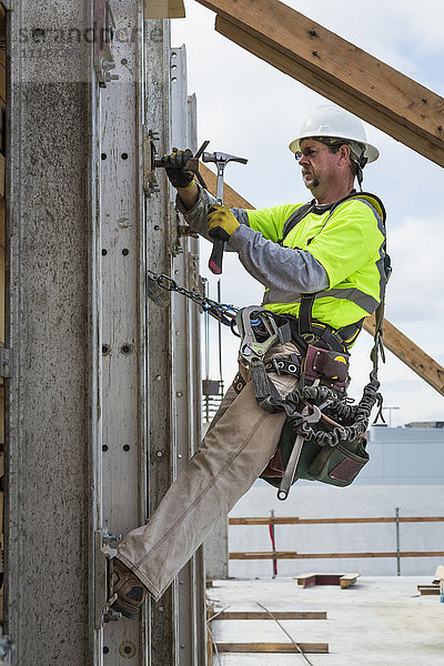 Kaukasischer Arbeiter hämmert Nägel auf einer Baustelle