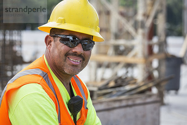 Hispanischer Arbeiter lächelt auf der Baustelle