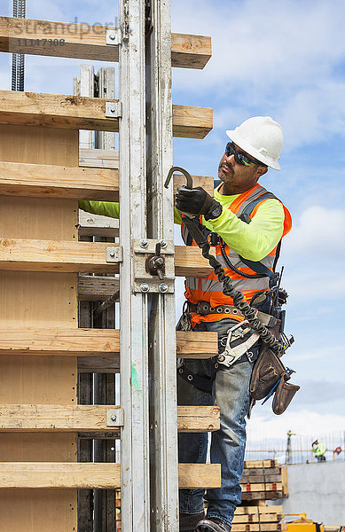 Hispanischer Arbeiter hält Haken auf der Baustelle