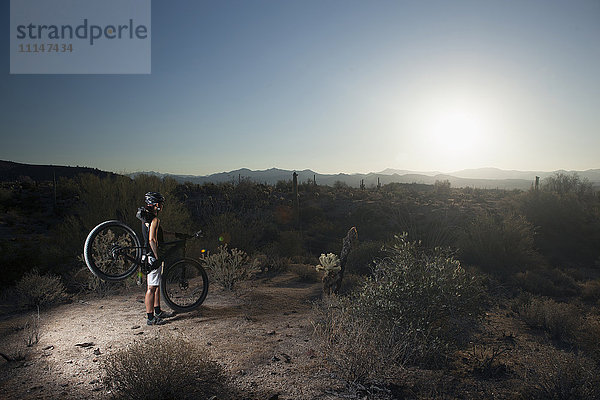 Mountainbiker in der Wüste stehend