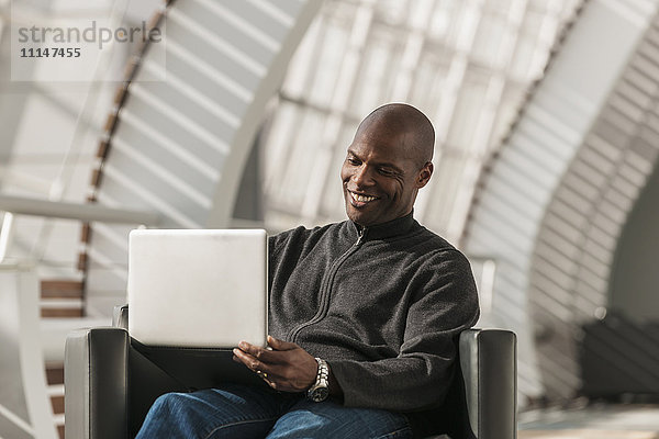 Afroamerikanischer Mann benutzt Laptop in der Lobby