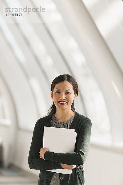 Japanische Geschäftsfrau mit Papieren in der Lobby