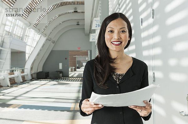 Japanische Geschäftsfrau mit Papieren im Büro