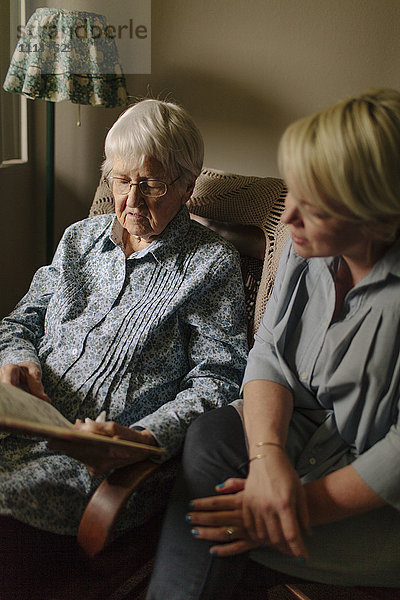 Ältere Frau liest ihrer Enkelin im Wohnzimmer vor