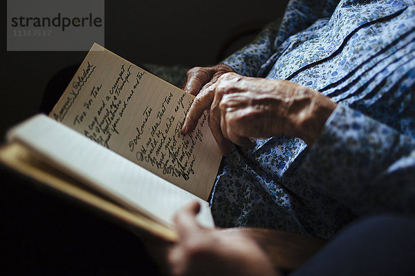 Ältere Frau liest ihrer Enkelin die Handschrift vor