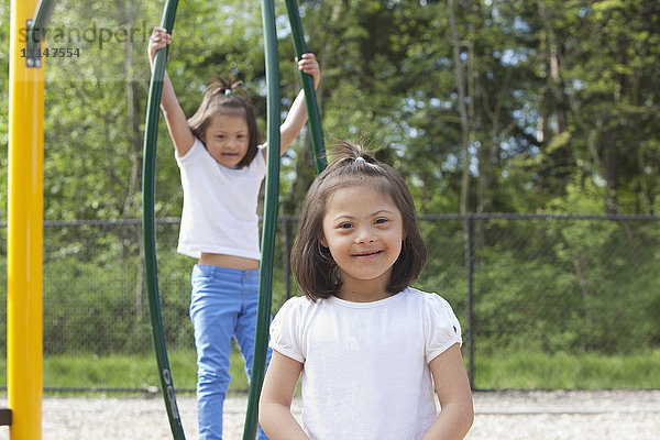 Gemischtrassige Mädchen mit Down-Syndrom lächelnd auf dem Spielplatz