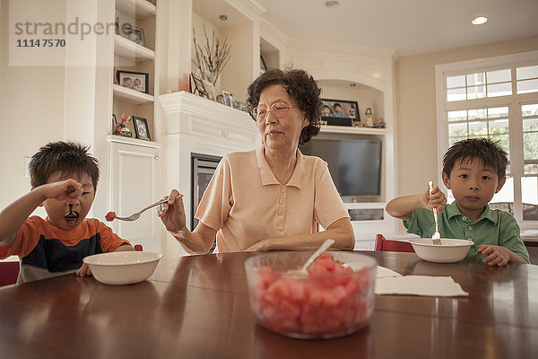Asiatische Großmutter füttert Enkel am Tisch