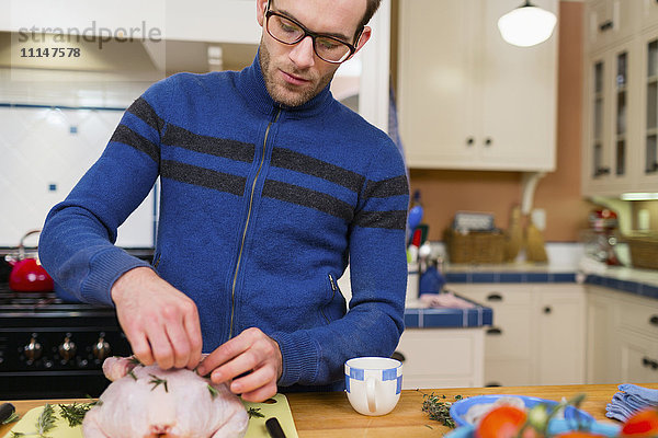 Kaukasischer Mann kocht Huhn in der Küche