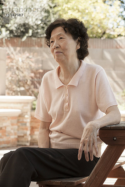 Ältere asiatische Frau sitzt am Picknicktisch
