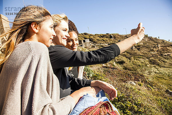 Frauen  die gemeinsam ein Handyfoto auf einem ländlichen Hügel machen