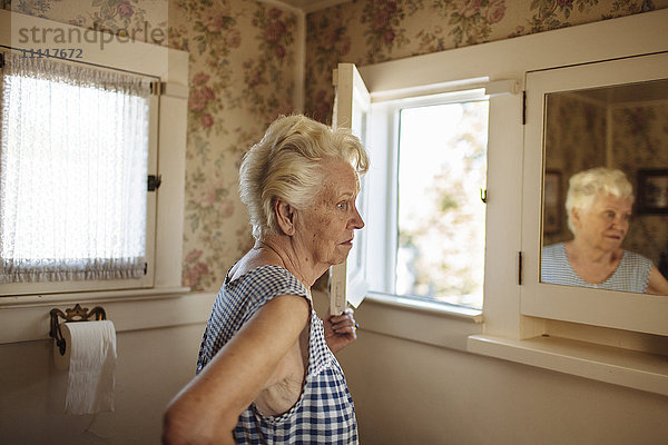 Ältere kaukasische Frau  die sich im Spiegel betrachtet