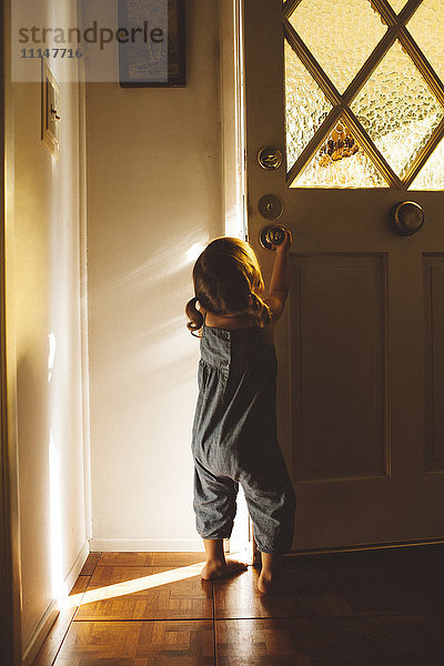 Hispanisches Mädchen im Vorschulalter beim Öffnen der Haustür
